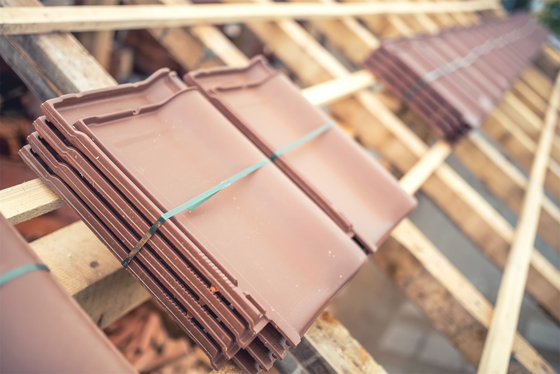 Bundles of clay roof tiles stacked on a roof deck.