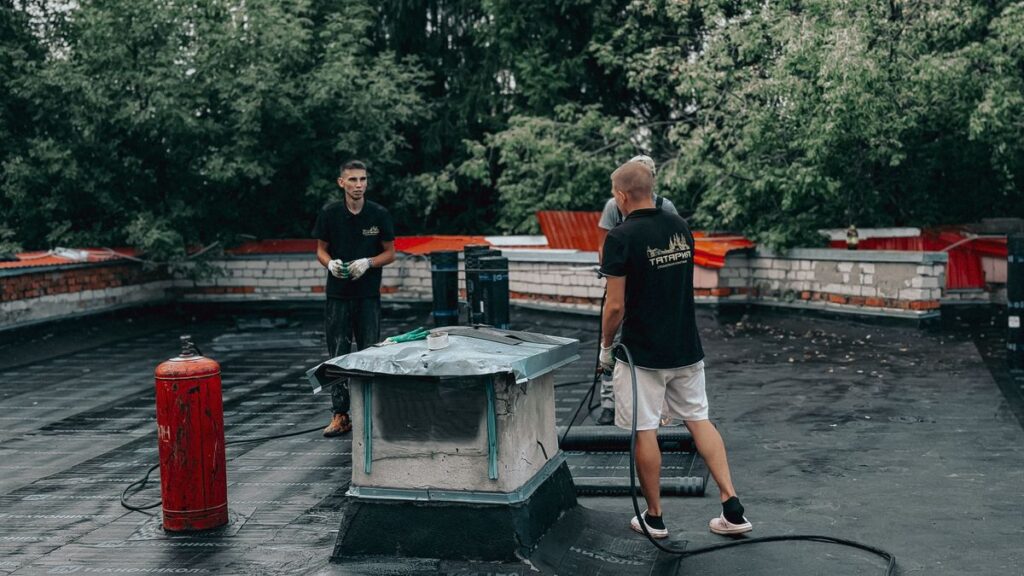 Two workers maintaining a flat commercial roof