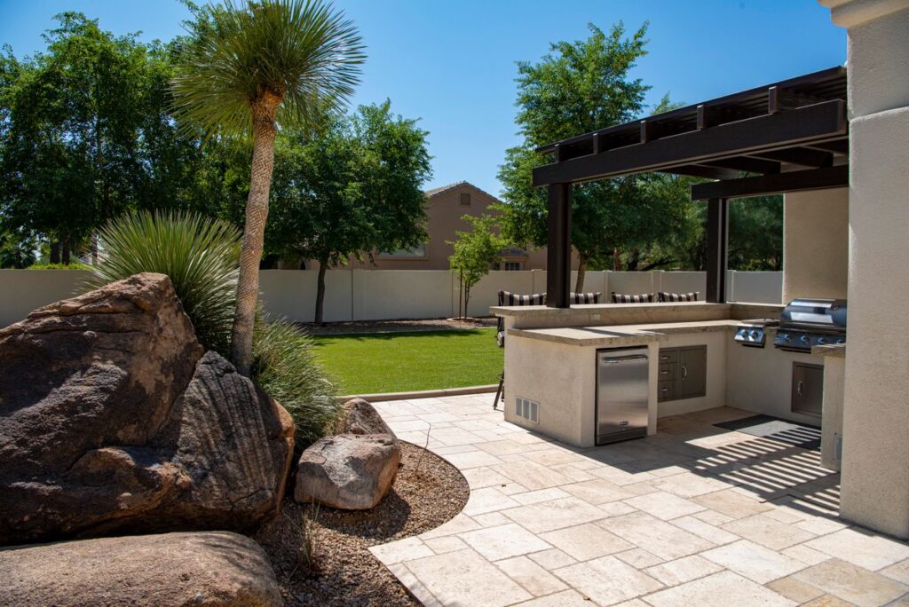 An outdoor kitchen with stone counters under a pergola